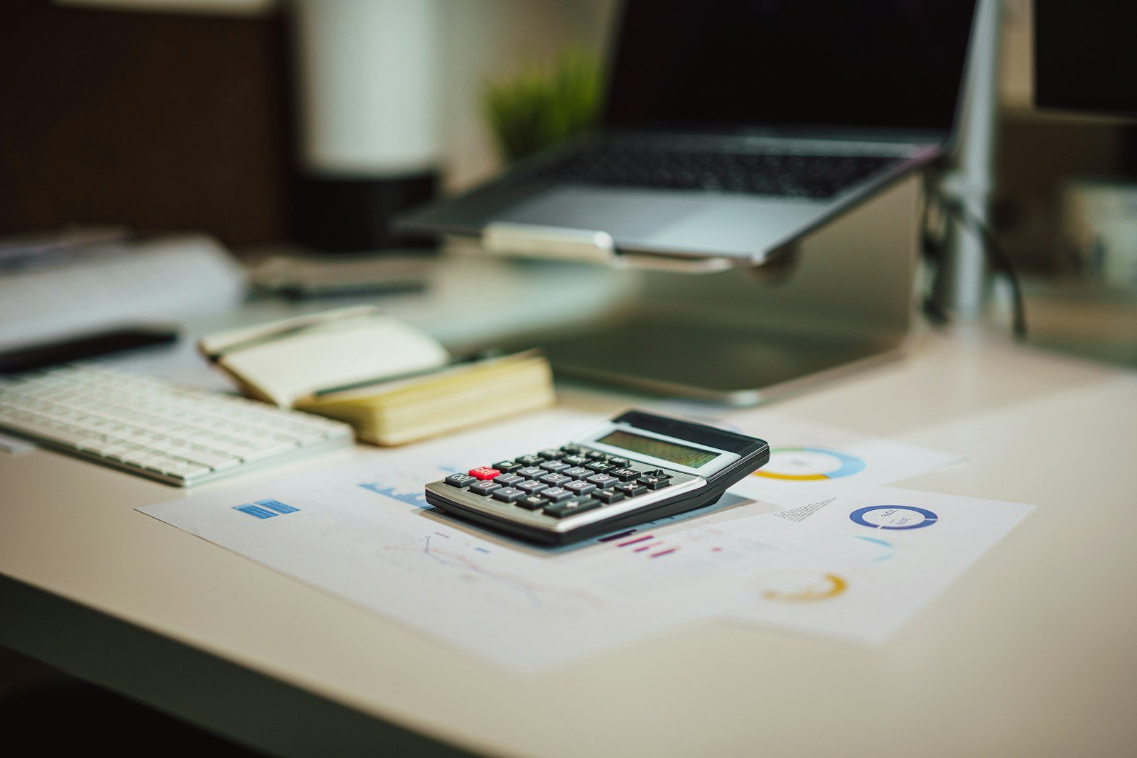 Calculadora, laptop y reportes sobre un escritorio